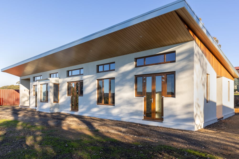 Long view along the north facade, showing the full run of glazing under the deep timber-lined eave